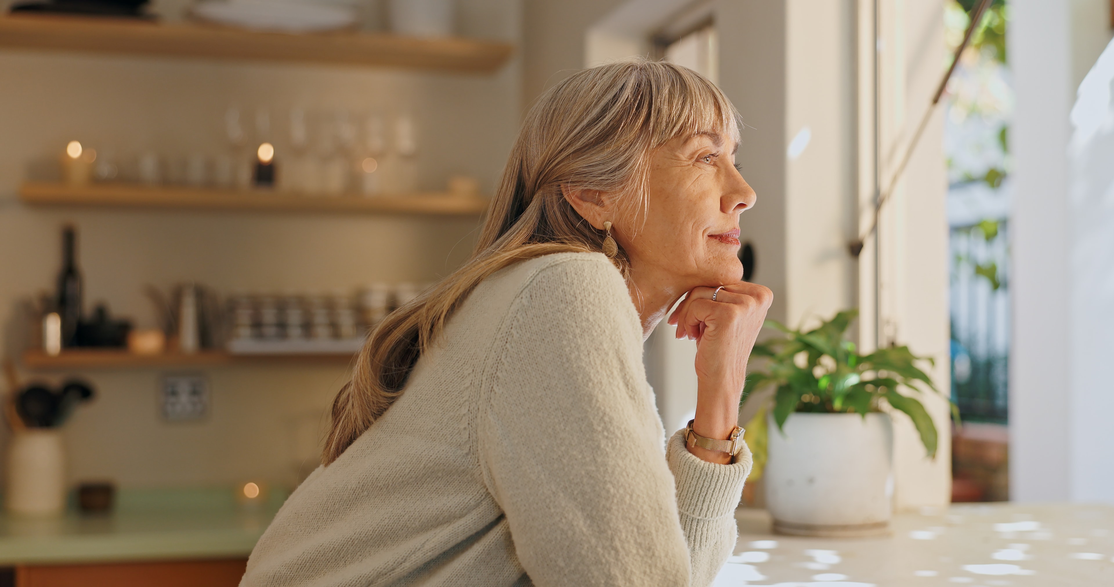 Woman leaning on a kitchen counter, looking outside